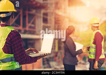 Businesswomen and foreman shake hands together. Engineer and manager teamwork and checking at site construction . Stock Photo