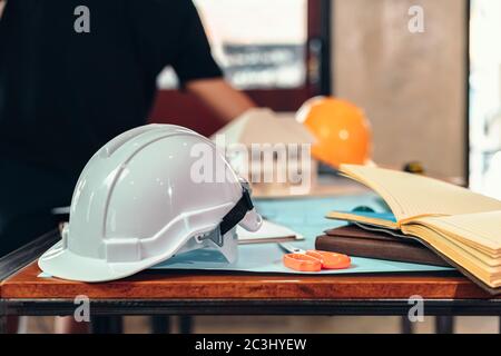 safety helmets  on the table at site construction. Architect, Engineer and businessman  read  planning background. Stock Photo