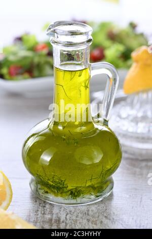 Flavored fresh natural olive oil with herbs and garlic in a glass sauce boat bottle, an ideal salad dressing. Stock Photo