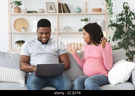 Stressed pregnant woman shouting at husband while he using laptop Stock Photo