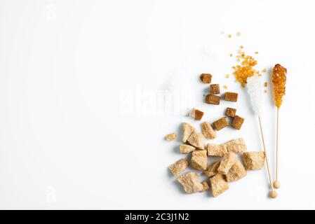 Various types of sugar brown cane, white granulated sugar, refined and crystal sugar stick on a white background, copy space. Top view. Stock Photo