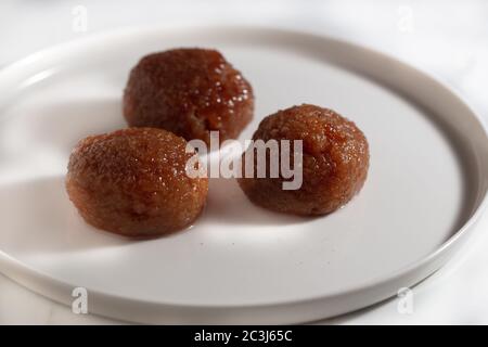 High angle shot of a white plate with three chocolate cookies on a white surface Stock Photo