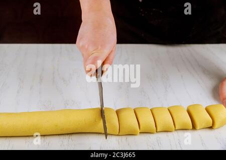 Chef cuts with a knife in equal portions for baking crispy buns. Stock Photo