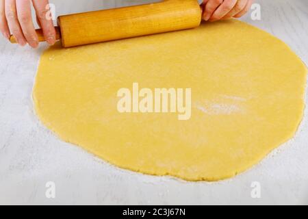 Woman rolling dough with pin for making sugar cookies on white table. Stock Photo