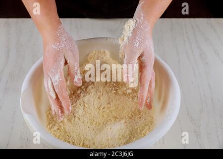 Woman kneading flour, sugar and butter with hands for making cookie dough. Stock Photo
