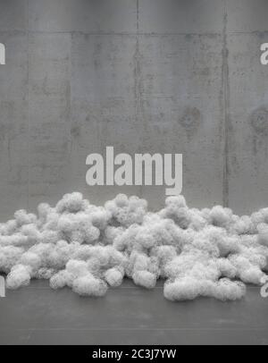 Creative composition of heaps of round skeins of wire on the background of an empty concrete wall. Installation of contemporary art in a minimalist de Stock Photo