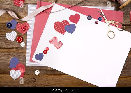 Scrapbooking background with craft paper, ribbon, buttons and heart cutouts. Space for your text. Stock Photo