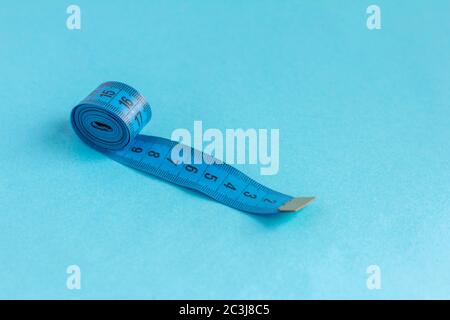 A roll of blue measuring tape on a blue background. Stock Photo