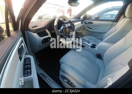 Moscow, Russia - May 09, 2019: White leather interior of an premium SUV Porsche Macan parked on the street. Package trim car of white oak and wooden heated steering wheel. Fisheye view Stock Photo