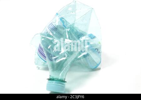 Closeup view of a crashed empty water bottle isolated on a white surface Stock Photo