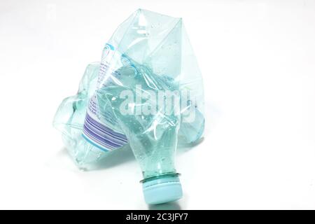 Closeup view of a crashed empty water bottle isolated on a white surface Stock Photo