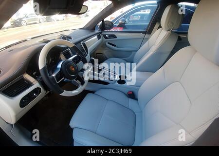 Moscow, Russia - May 09, 2019: White leather interior of an premium SUV Porsche Macan parked on the street. Package trim car of white oak and wooden heated steering wheel. Stock Photo