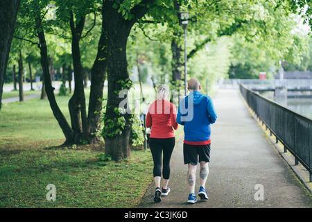 MUNICH, GERMANY - May 03, 2020: Couple jogging together in the early morning in a Munich park. Early morning exercise as a morning routine. Fitness de Stock Photo