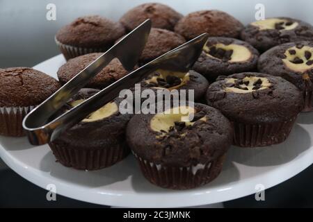 Assorted chocolate chip, marble chocolate, and apple muffins on a cake tray Stock Photo