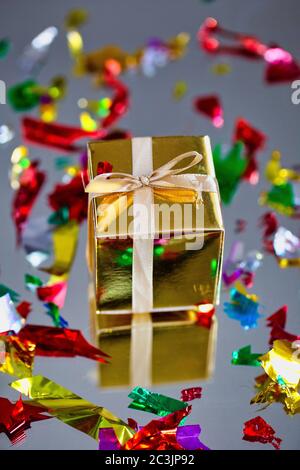 Group of gold sparkling gift boxes on grey background with reflection and confetti. A set of gold gift boxes for present, suprise,birthday,Christmas Stock Photo