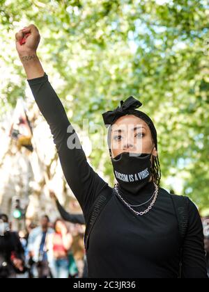 London, UK. 20th June, 2020. A protestor walks through London with her fist raised in solidarity during the Black Lives Matter protest. Credit: Yousef Al Nasser/ Alamy Live News Stock Photo