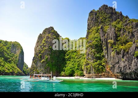 Beautiful tropical landscape with turquoise water and green cliffs, tourist boat in ocean, El Nido, Palawan, Philippines Stock Photo