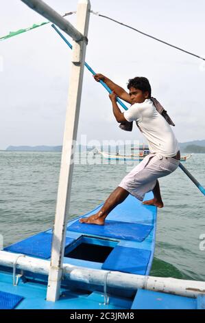 SABANG, PALAWAN, PHILIPPINES - OCTOBER 11, 2012: Unidentified young male row a boat with tourists to an Underground River. Stock Photo