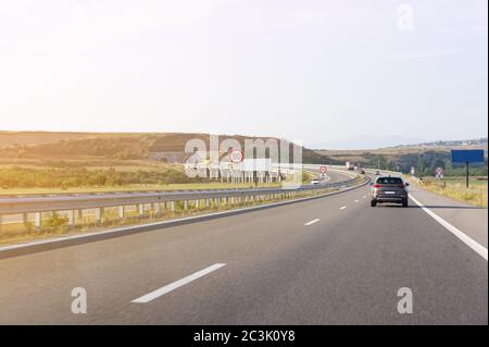 crossover car driving fast on asphalt road. the road in front of the tunnel. speed limit signs Stock Photo