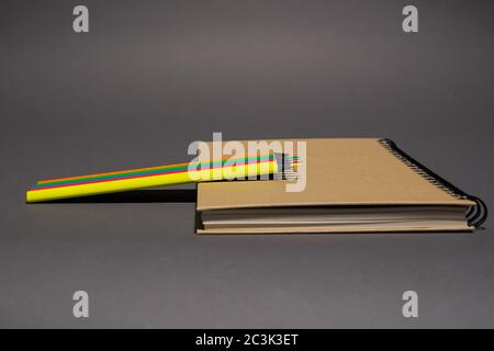 closed notebook with craft cover and spiral mount lies on gray background, color pencils lie on notebook Stock Photo