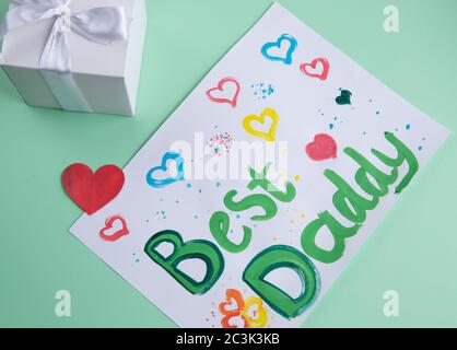 gift box and child's drawing on the table. Congratulations on father's day. Stock Photo