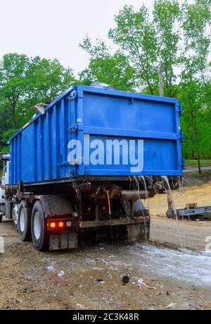 Loaded dumpster near a litterless metal container without a cover is full of construction debris waste standing in the building under construction Stock Photo