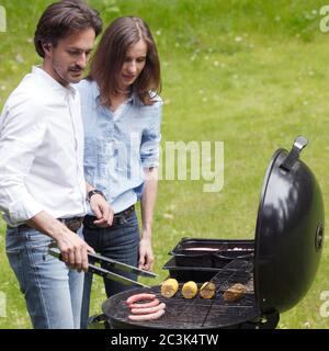 Couple cooking food corn vegetables sausage on barbecue grill at backyard Stock Photo
