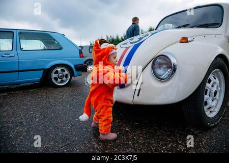 Moscow, Russia: July 06, 2019: A small child in a fox costume stands near a restored Volkswagen beetle and examines it with interest. Stock Photo