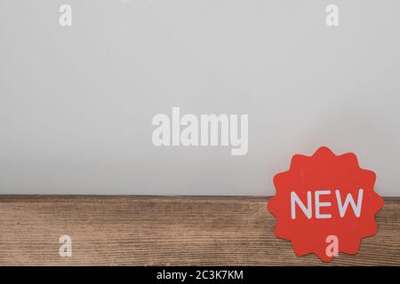 Closeup shot of an orange [NEW] sign on the wooden table under the lights Stock Photo