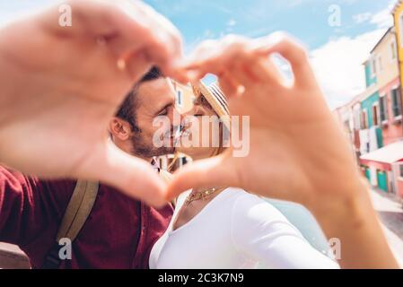 Close up of young couple in love making heart shape with hands outdoor at vacation.