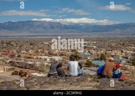 Families on a hiking trail in Petroglyph National Monument overlooking the city of Albuquerque and the Sandia Mountains