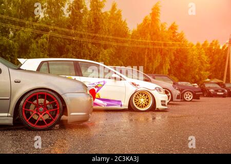 Moscow, Russia - July 19, 2019: Tuned low sport hatchback with red Candy colored alloy wheels. Volkswagen Golf mk 4 is on the street near golf 7 with decals Stanced lowrider with badboy hood. Stock Photo