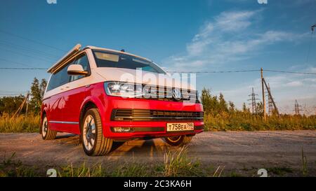 St. Petersburg, Russia - July 22, 2019: Red and white colored modern Volkswagen Multivan California Ocean (Transporter T6). Is parked on the country road. Front view Stock Photo