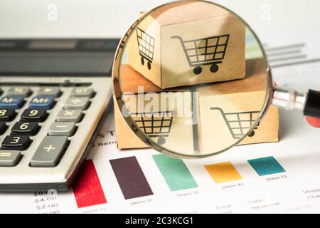 Shopping cart box, magnifying glass and calculator on chart graph background, business import export investment online finance concept. Stock Photo