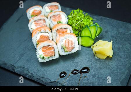 Sushi, traditional Japanese cuisine. Delicious Uramaki on decorated plate, black background. Stock Photo