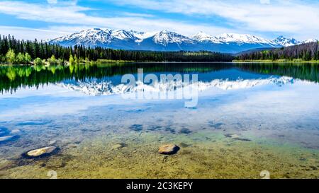 Patricia Lake with reflections of the snow capped peaks of the Rocky Mountains in Jasper National Park, Alberta, Canada Stock Photo