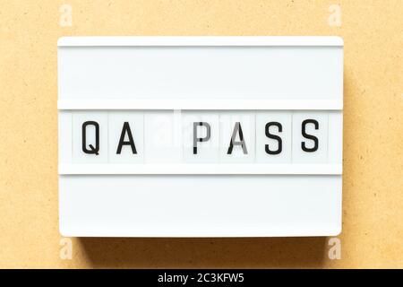 Lightbox with word QA (Abbreviation of Quality Assurance) pass on wood background Stock Photo
