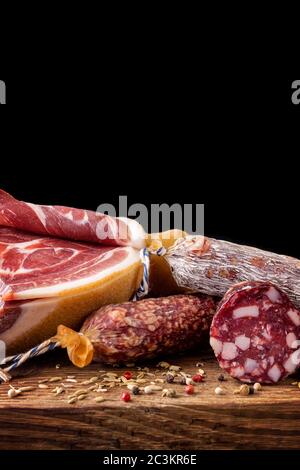 Traditional sausage , sausage with mold and spanish ham( bellota, jamon). Sliced sausage salami on wooden board with spices: pepper and fennel. Close- Stock Photo