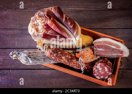 Traditional sausage and sausage with mold , jamon, bacon in wooden box on wooden background . Close-up.  Top view. Element for design Stock Photo