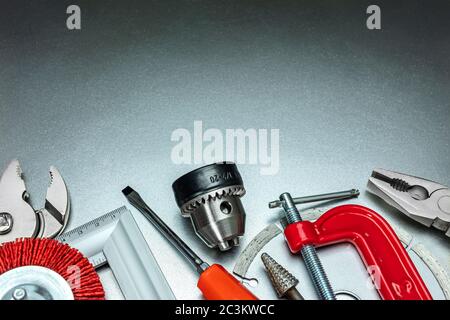 set of different tools including pliers, screwdriver, clamp, drill and grinding wheel on metal background. hand tools for construction and repair Stock Photo