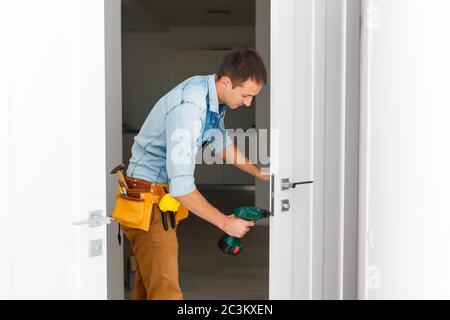 Master with screwdriver installs door hinges. Stock Photo