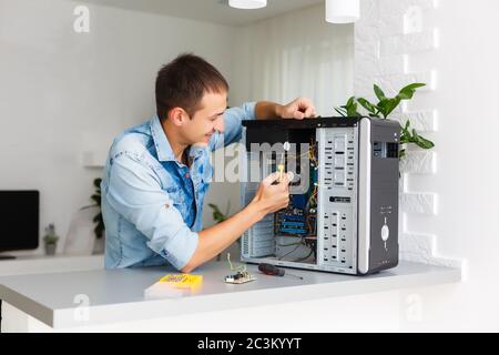 Young technician working on broken computer in his office Stock Photo