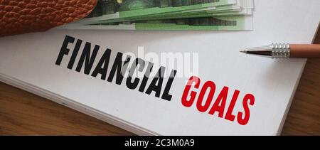 Financial goals written on page of copybook and 100 Euro bills put on it . Business and career big salary saving and investment concept. Stock Photo