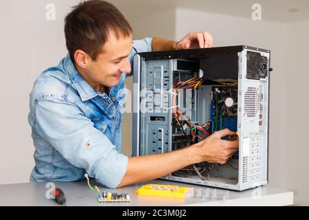 Young technician working on broken computer in his office Stock Photo