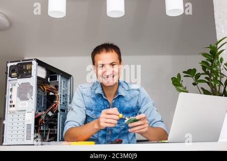 Young technician working on broken computer in his office Stock Photo