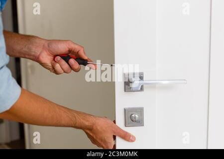 Master with screwdriver installs door hinges. Stock Photo