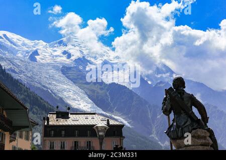 Stunning view of Mont Blanc, highest peak of Alps, from Chamonix in summer sunny day, blue sky cloud in background, statue of Michel Gabriel Paccard, Stock Photo