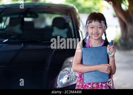 Asian little girl student wearing face shield during she going back to school after covid-19 quarantine. Stock Photo