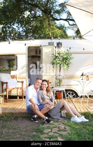 Young american couple sitting near house on wheels and hugging. Stock Photo