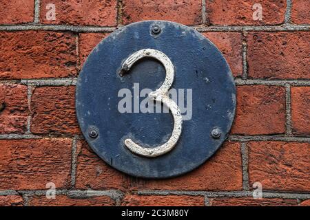 3 Digit on Dark Metal Background on red brick wall. Number three Stock Photo